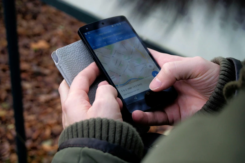 a close up of a person holding a cell phone, a picture, google maps, material design, outdoors, definition