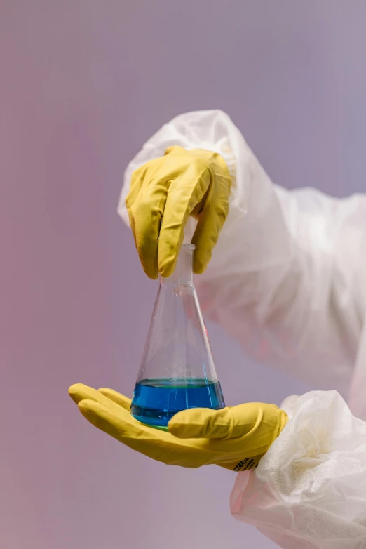 a person holding a flask filled with blue liquid, an album cover, shutterstock, plasticien, yellow latex gloves, made of nanomaterials, labcoat, trending photo