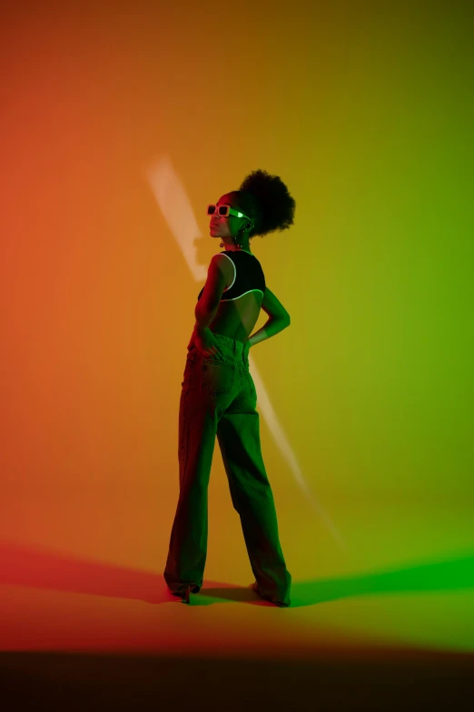 a woman standing in front of a colorful background, an album cover, pexels, funk art, full body backlight, green lights, ashteroth, lens flare glow