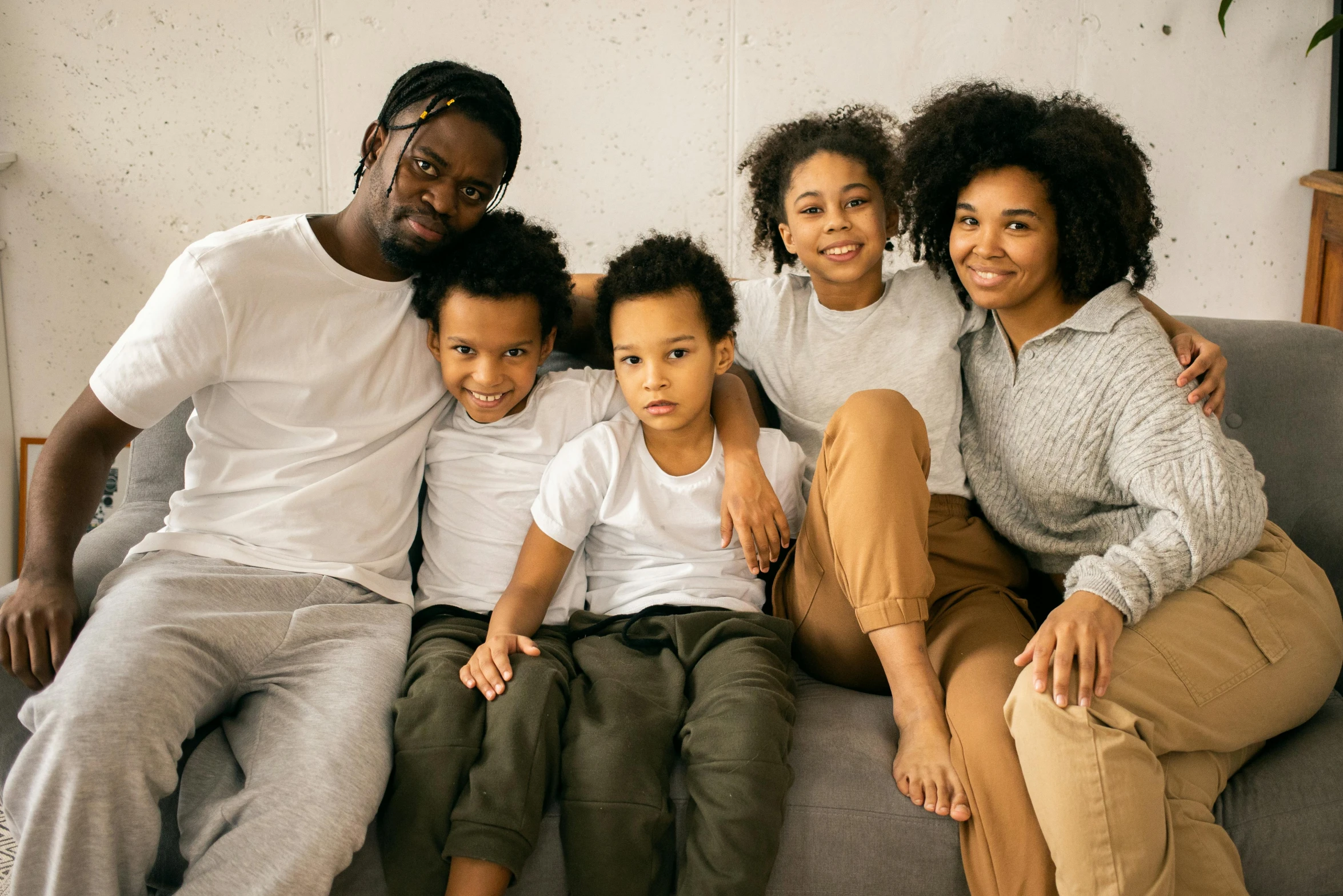 a group of people sitting on top of a couch, pexels, husband wife and son, black teenage boy, neutral colours, for kids