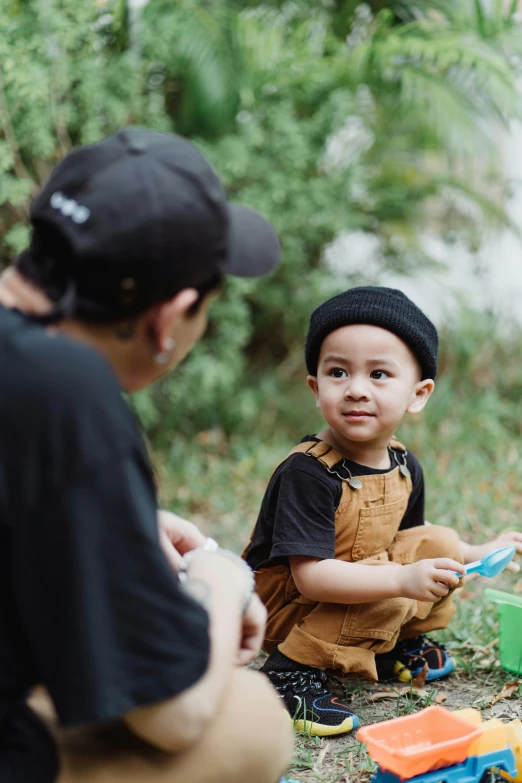 a man sitting on the ground next to a little boy, by Yosa Buson, pexels contest winner, cardistry, having a picnic, curious expression, gif