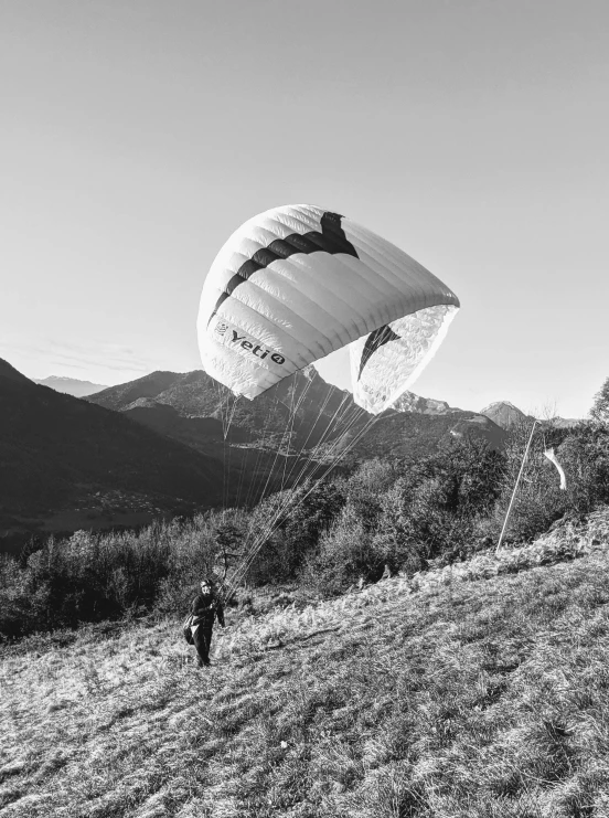 a black and white photo of a person paragliding, by Emma Andijewska, back, benoit b, beautiful surroundings, high