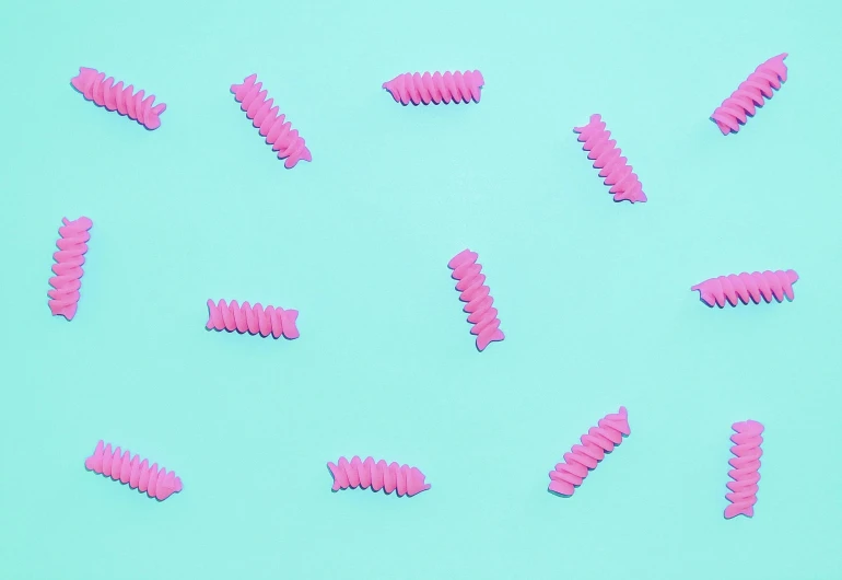 a group of pink toothbrushes sitting on top of a blue surface, an album cover, by Rachel Reckitt, trending on pexels, pop art, intricate pasta waves, larvae, pattern, made of candy