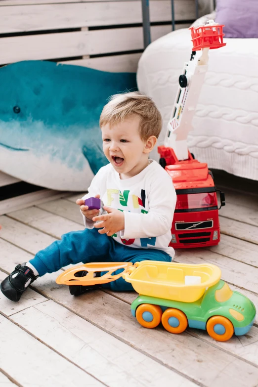 a little boy sitting on the floor playing with toys, inspired by Sam Havadtoy, happening, vehicle, multicoloured, david a, white