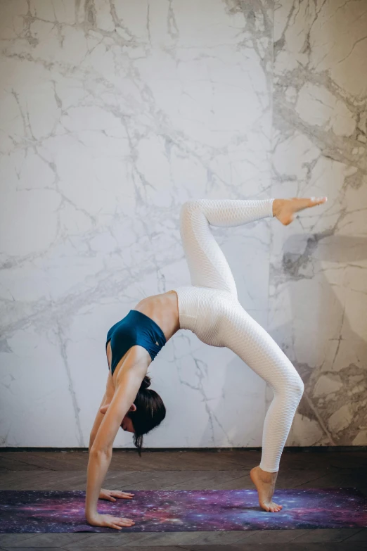 a woman doing a handstand pose on a yoga mat, a marble sculpture, by Arabella Rankin, pexels contest winner, arabesque, white leggings, back arched, marble room, brunette fairy woman stretching