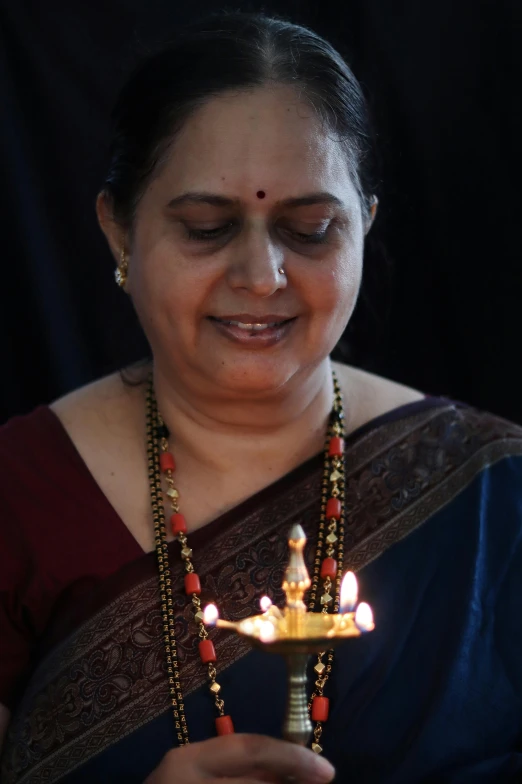 a woman holding a lit oil lamp in her hand, inspired by T. K. Padmini, cake, profile image, wearing jewellery, 2019 trending photo