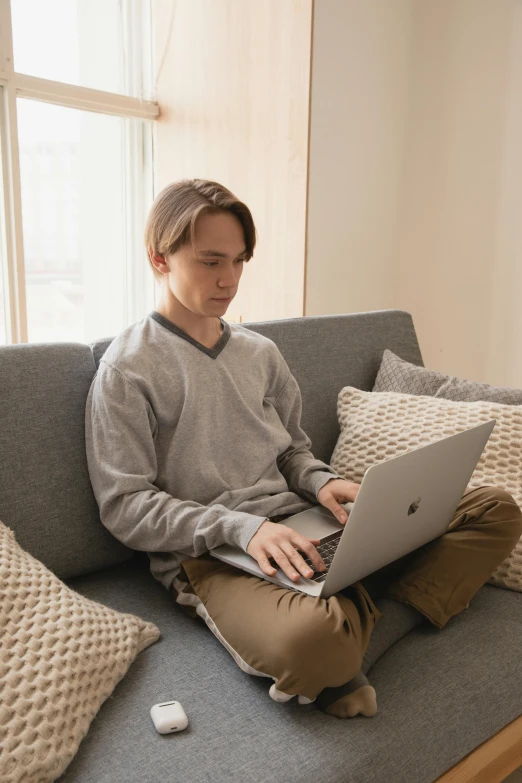 a person sitting on a couch with a laptop, liam, grey, computer science, concentration