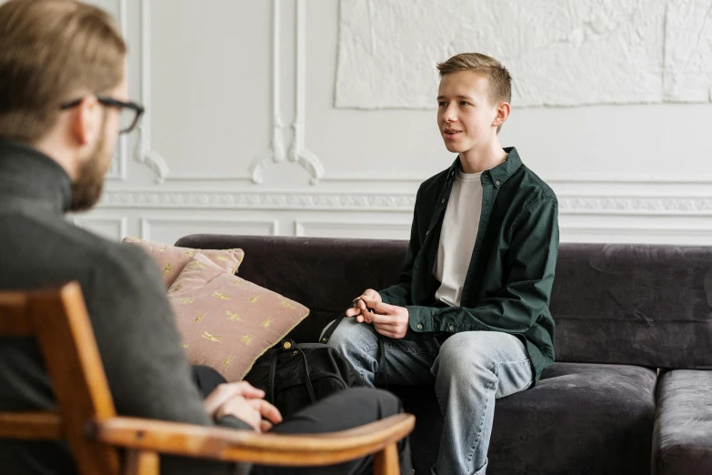 a man sitting on a couch talking to another man, by Sebastian Vrancx, pexels, portrait of 1 5 - year - old boy, 15081959 21121991 01012000 4k, lachlan bailey, centre image
