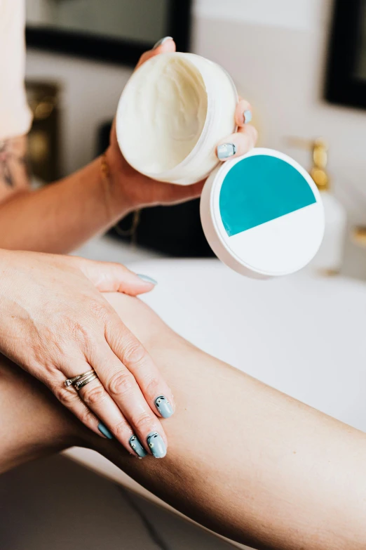 a woman sitting on top of a bath tub holding a cup, by Arabella Rankin, trending on pexels, white and teal metallic accents, temporary tattoo, closeup of arms, candy treatments
