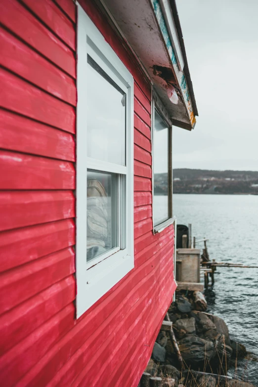 a red house next to a body of water, by Julia Pishtar, pexels contest winner, leaning against the window, shack close up, view of the ocean, quebec