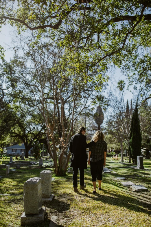 a man and a woman walking through a cemetery, los angelos, profile image, lush surroundings, cast