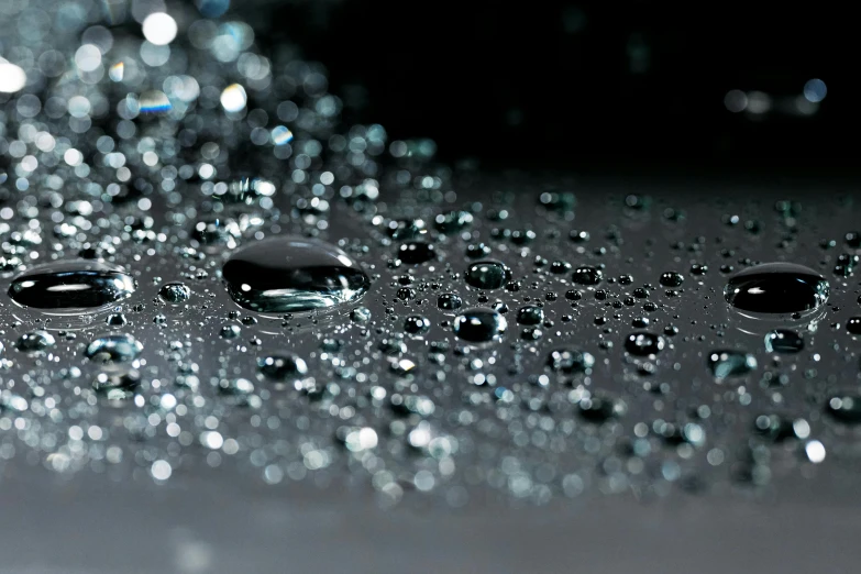 a close up of water droplets on a surface, 2 0 % pearlescent detailing, shiny reflective surfaces, with a black background, drops are falling from above