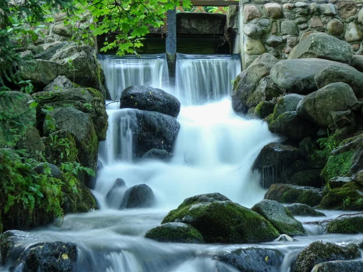 a small waterfall flowing through a lush green forest, by Jesper Knudsen, pexels contest winner, hurufiyya, water wheel, panels, 2 5 6 x 2 5 6 pixels, urban surroundings