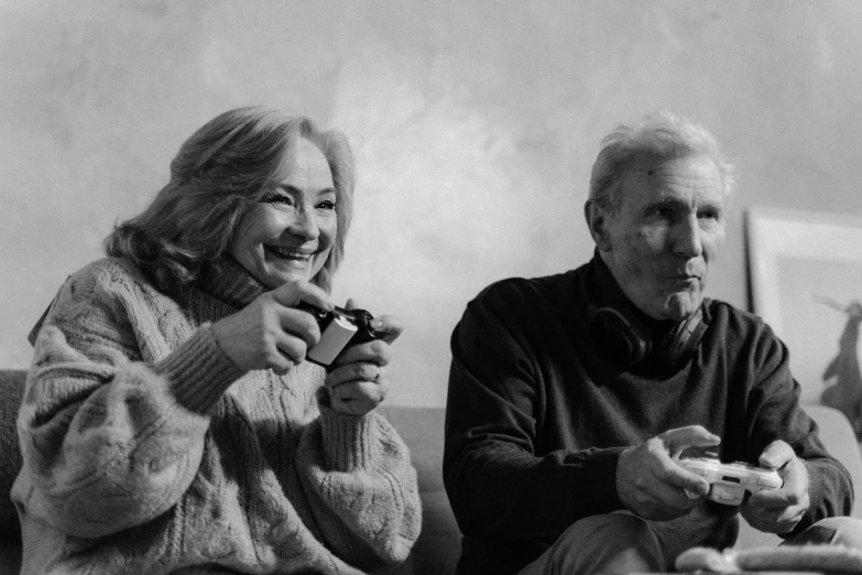 a black and white photo of two people sitting on a couch, a black and white photo, pexels, photorealism, playing video games, two old people, eating cheese, nvidia promotional image