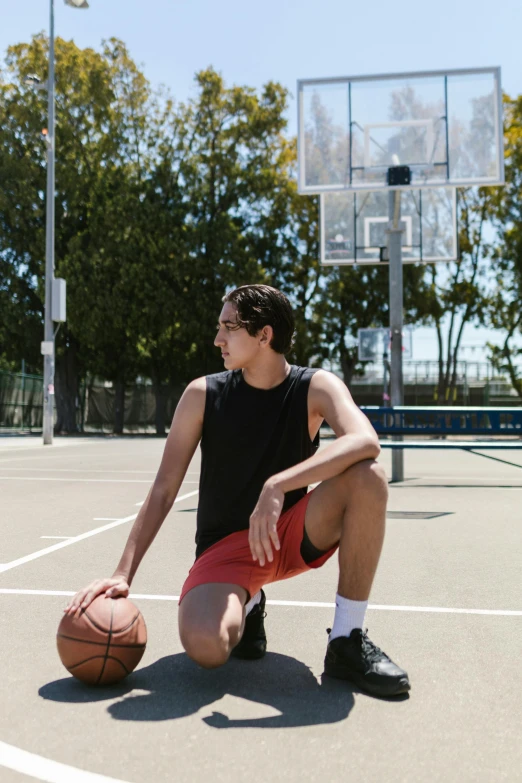 a man kneeling on a basketball court holding a basketball, tight black tank top and shorts, asher duran, bay area, androgynous person