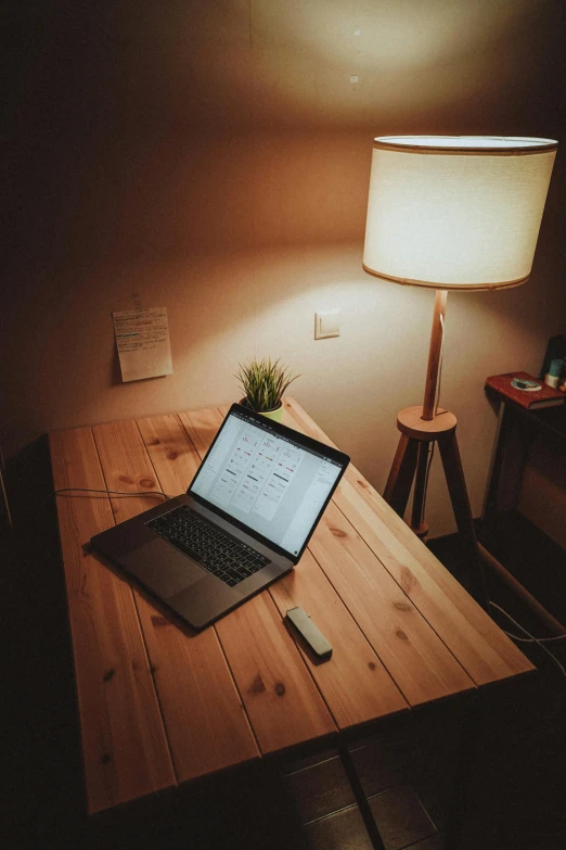 a laptop computer sitting on top of a wooden table, lamps, on a table