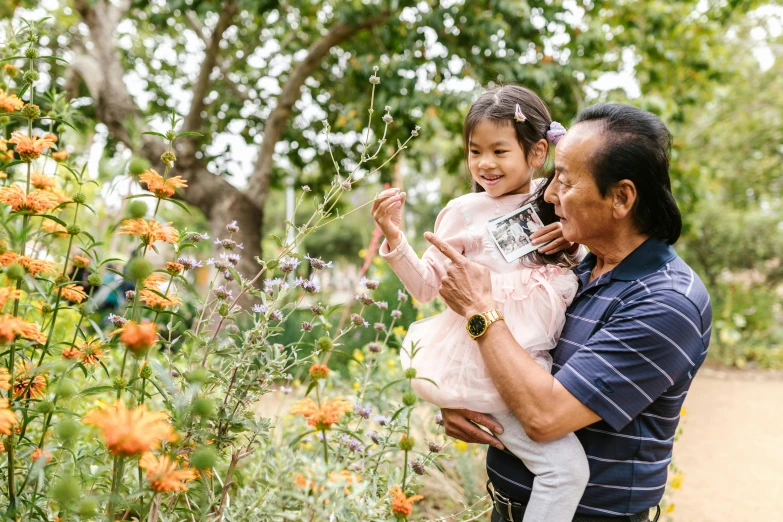 a man holding a little girl in a garden, unsplash, avatar image, darren quach, vine and plants and flowers, an oldman