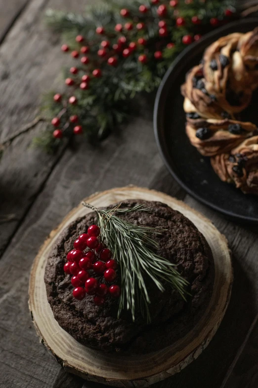 a couple of pastries sitting on top of a wooden table, a still life, by Daarken, unsplash, evergreen branches, round format, “berries, black