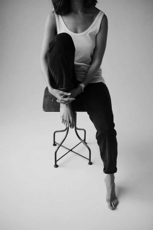 a black and white photo of a woman sitting on a chair, a black and white photo, by Clifford Ross, unsplash, pointe pose, casual pose, sitting on bent knees, portait image