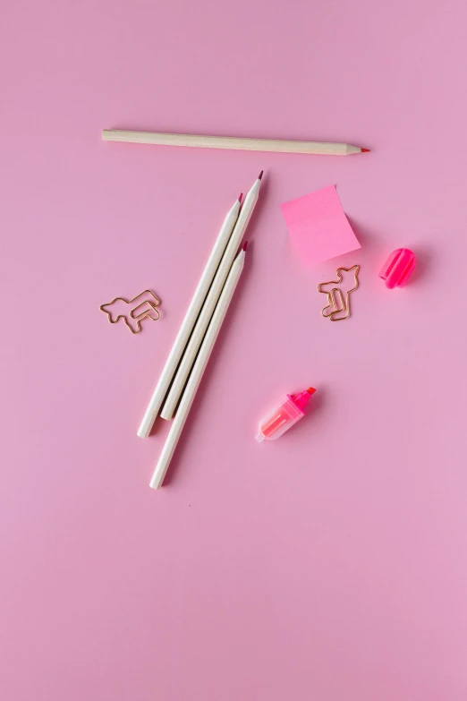 a pair of pencils sitting on top of a pink surface, various items, stick figure, top - down photograph, without text