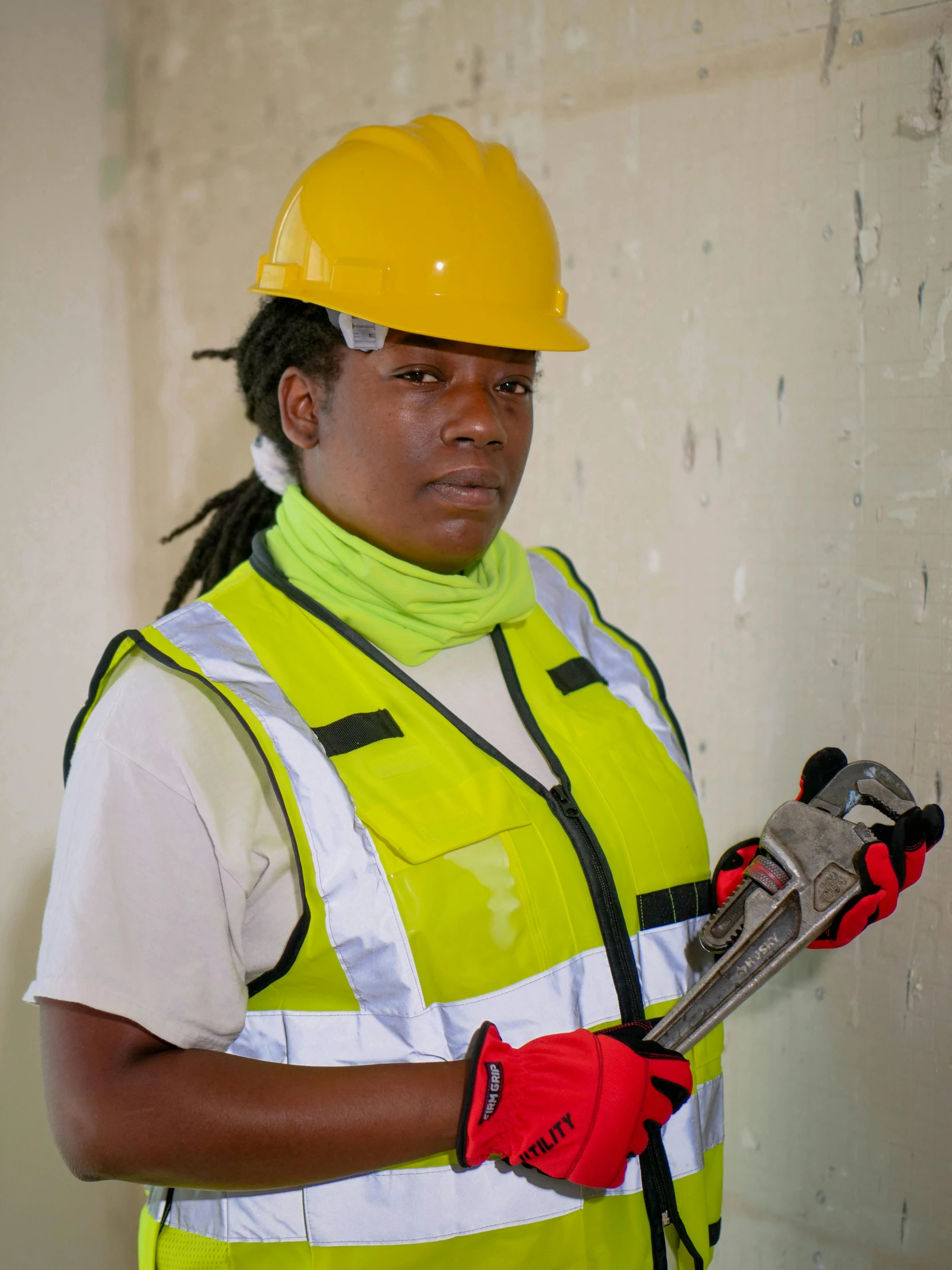 a woman in a hard hat holding a wrench, a portrait, by Dorothy Bradford, pexels contest winner, bulletproof vest, wearing hi vis clothing, mongezi ncaphayi, lgbtq