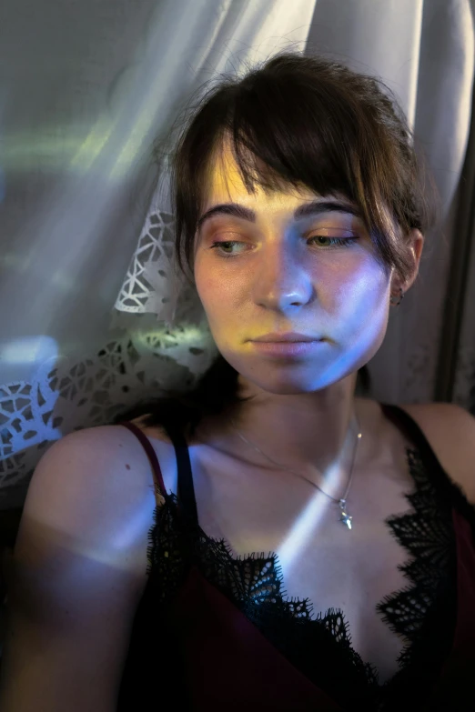 a woman sitting in front of a window holding a cell phone, inspired by Nan Goldin, photorealism, police lights shine on her face, looking exhausted, sat down in train aile, photo of young woman