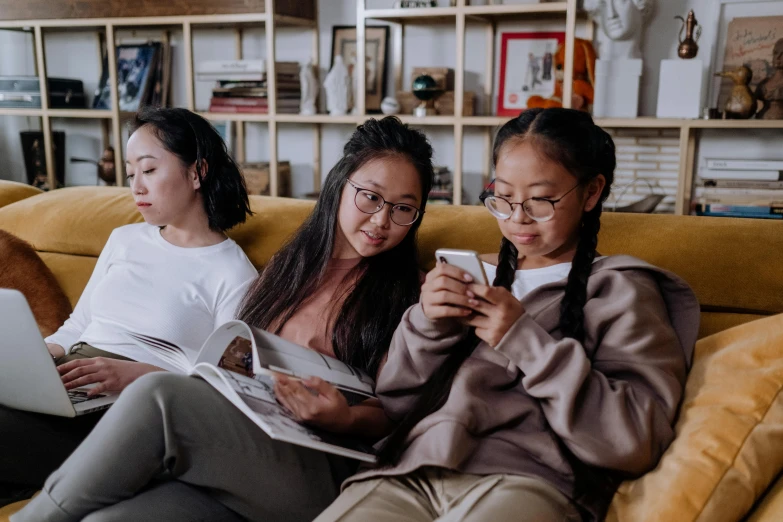 three women sitting on a couch looking at their cell phones, a cartoon, trending on pexels, young asian girl, textbooks and books, kids, realistic »