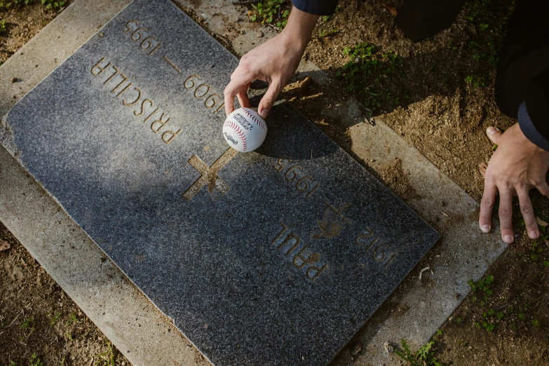 a person placing a baseball on a grave, golf digest, dezeen, tombstone, dirt stains