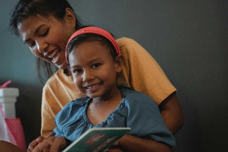 a woman reading a book to a little girl, a portrait, pexels contest winner, hurufiyya, both smiling for the camera, avatar image, bedhead, malaysian