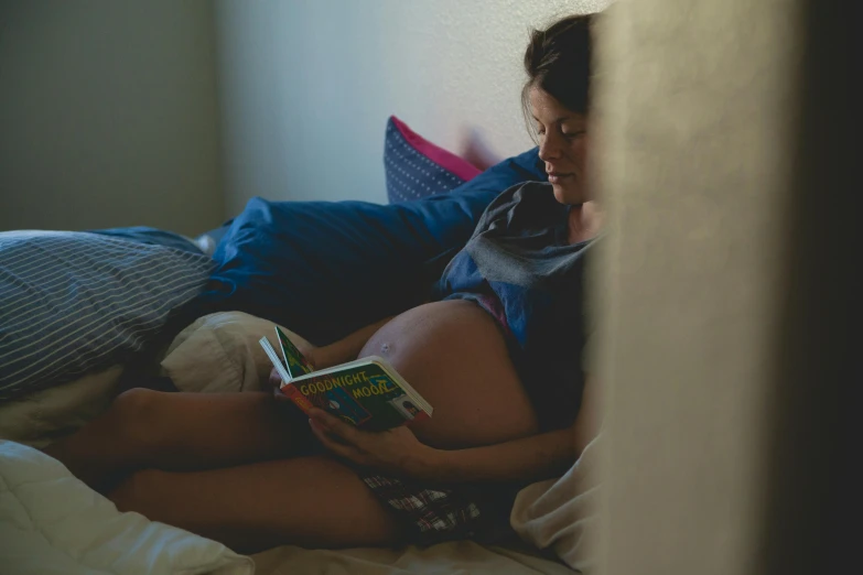 a pregnant woman reading a book on a bed, by Elsa Bleda, pexels, happening, shot from cinematic, ( ultra realistic, ignant, high resolution