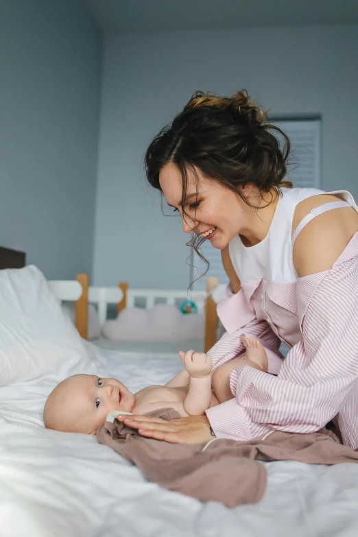 a woman playing with a baby on a bed, pexels contest winner, smirking, square, clean design, low quality photo