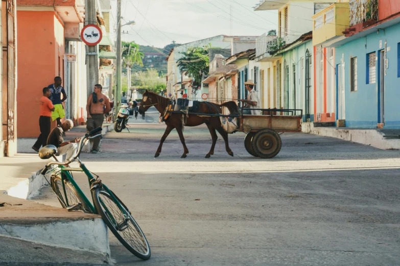 a horse pulling a cart down a street, pexels contest winner, caribbean, square, small town surrounding, bicycle in background