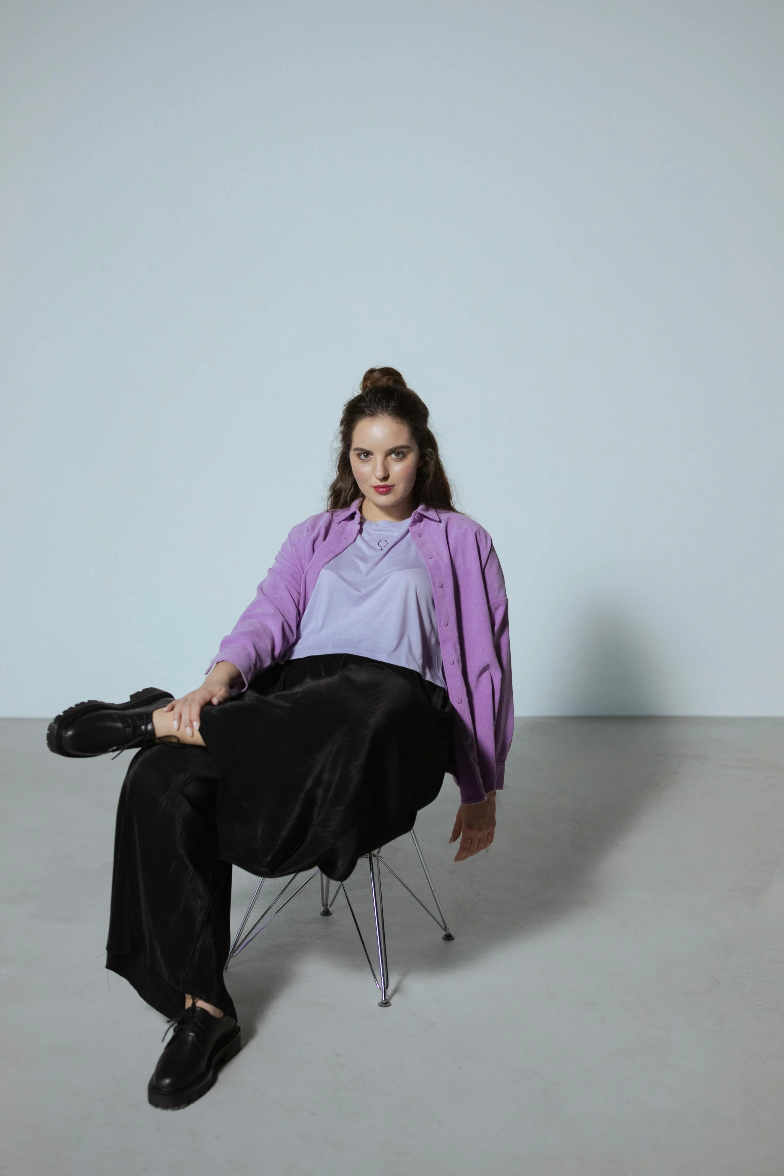 a woman sitting on a chair in a room, an album cover, unsplash, realism, wearing a purple sweatsuit, portrait sophie mudd, ((purple)), pastel clothing