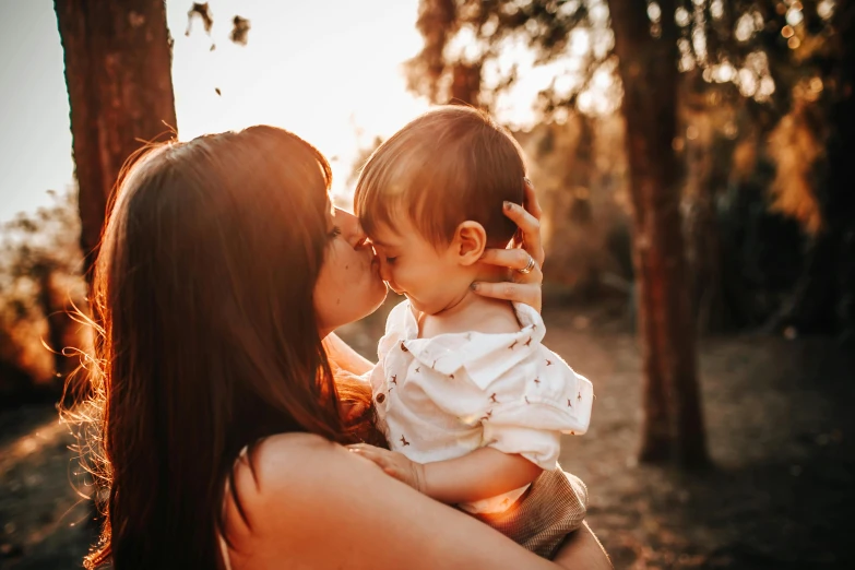 a woman holding a baby in her arms, pexels contest winner, (golden hour), avatar image, lesbian, manuka