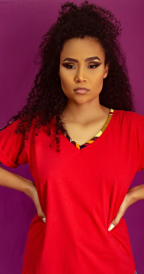 a woman posing with her hands on her hips, an album cover, by Chinwe Chukwuogo-Roy, trending on pexels, red t-shirt, wearing v - neck top, vibrant color with gold speckles, avatar image