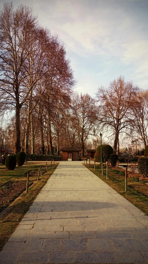 a walkway in a park with trees in the background, an album cover, inspired by Albert Paris Gütersloh, unsplash, village square, brown, medium format. soft light, february)