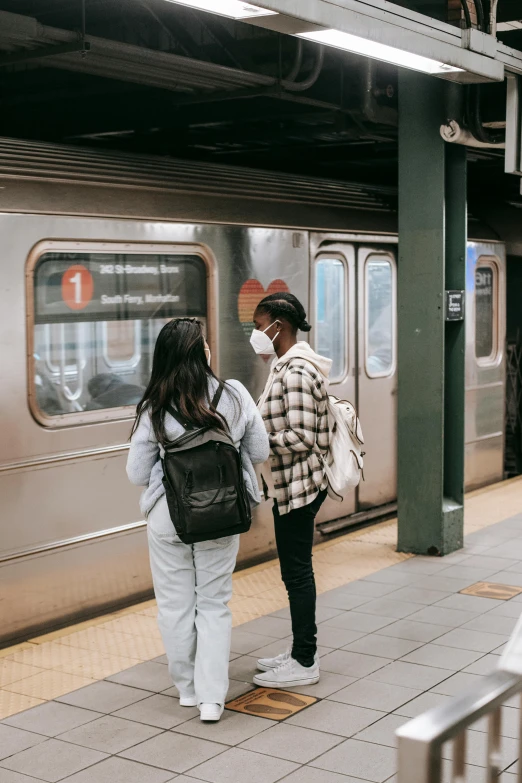 a couple of people that are standing in front of a train, trending on unsplash, mta subway entrance, pandemic, her back is to us, ignant