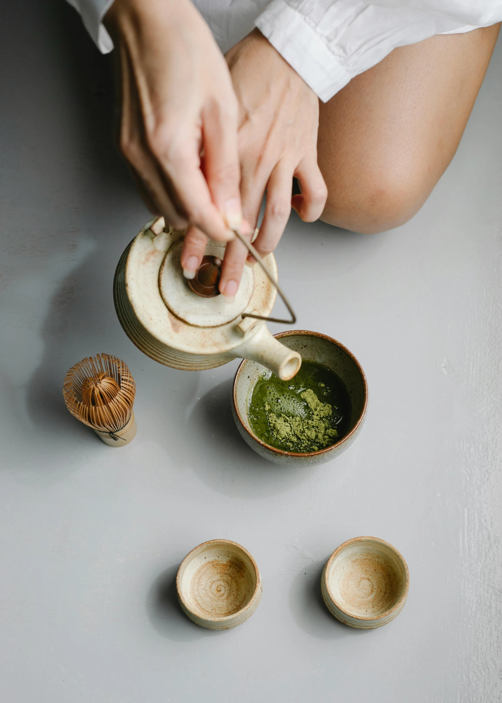 a woman is pouring a cup of green tea, inspired by Kanō Shōsenin, dau-al-set, curated collections, high angle, ceramic, alessio albi