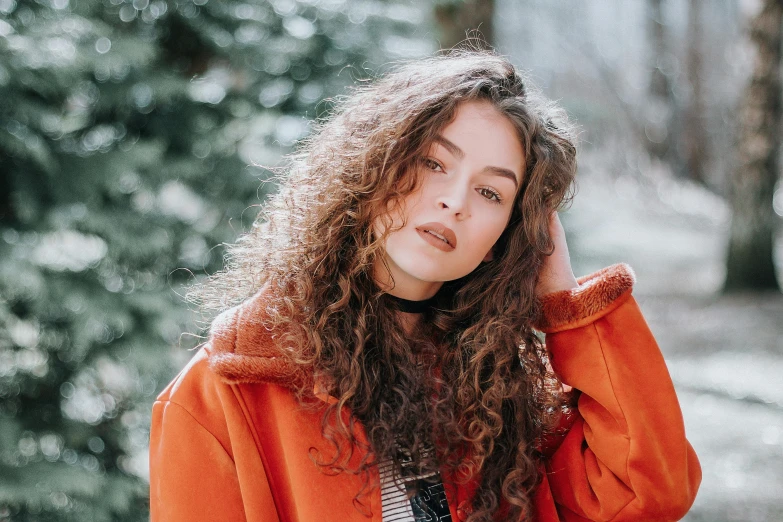 a woman with long curly hair wearing an orange jacket, pexels contest winner, antipodeans, winter vibes, charli bowater and artgeem, brown haired, hair : long brown