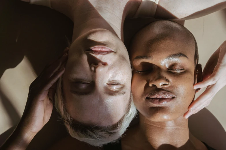 a man and a woman laying on top of each other, by Matija Jama, trending on pexels, renaissance, african facial features, lesbian, pale glowing skin, pearlescent skin