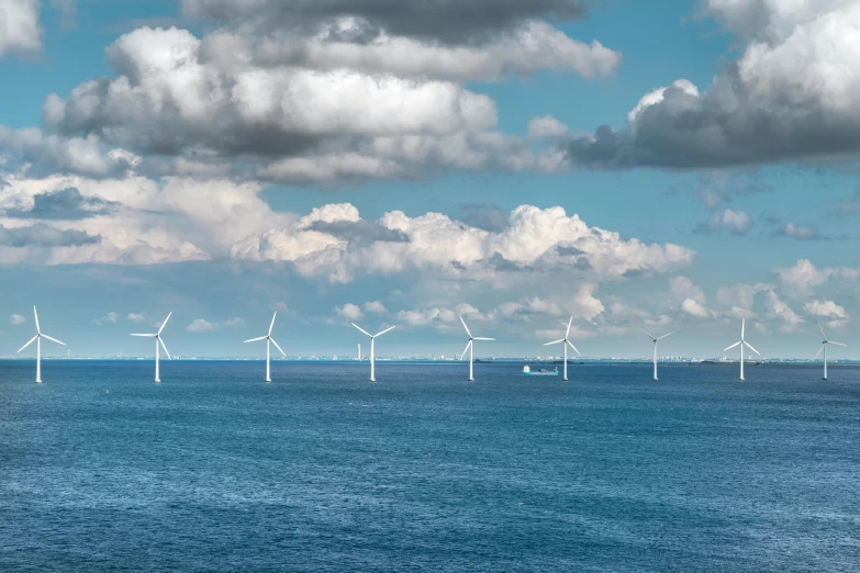 a large group of wind turbines in the ocean, a colorized photo, by Jesper Knudsen, pexels contest winner, under blue clouds, thumbnail, slide show, minimalist