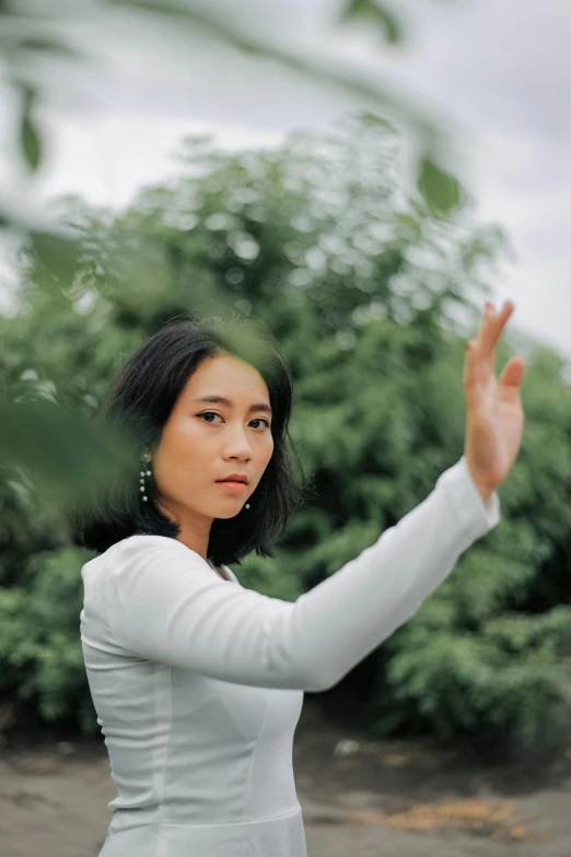 a woman in a white shirt is throwing a frisbee, an album cover, inspired by Tang Yifen, unsplash, standing in a botanical garden, partially cupping her hands, portrait image, li bingbing