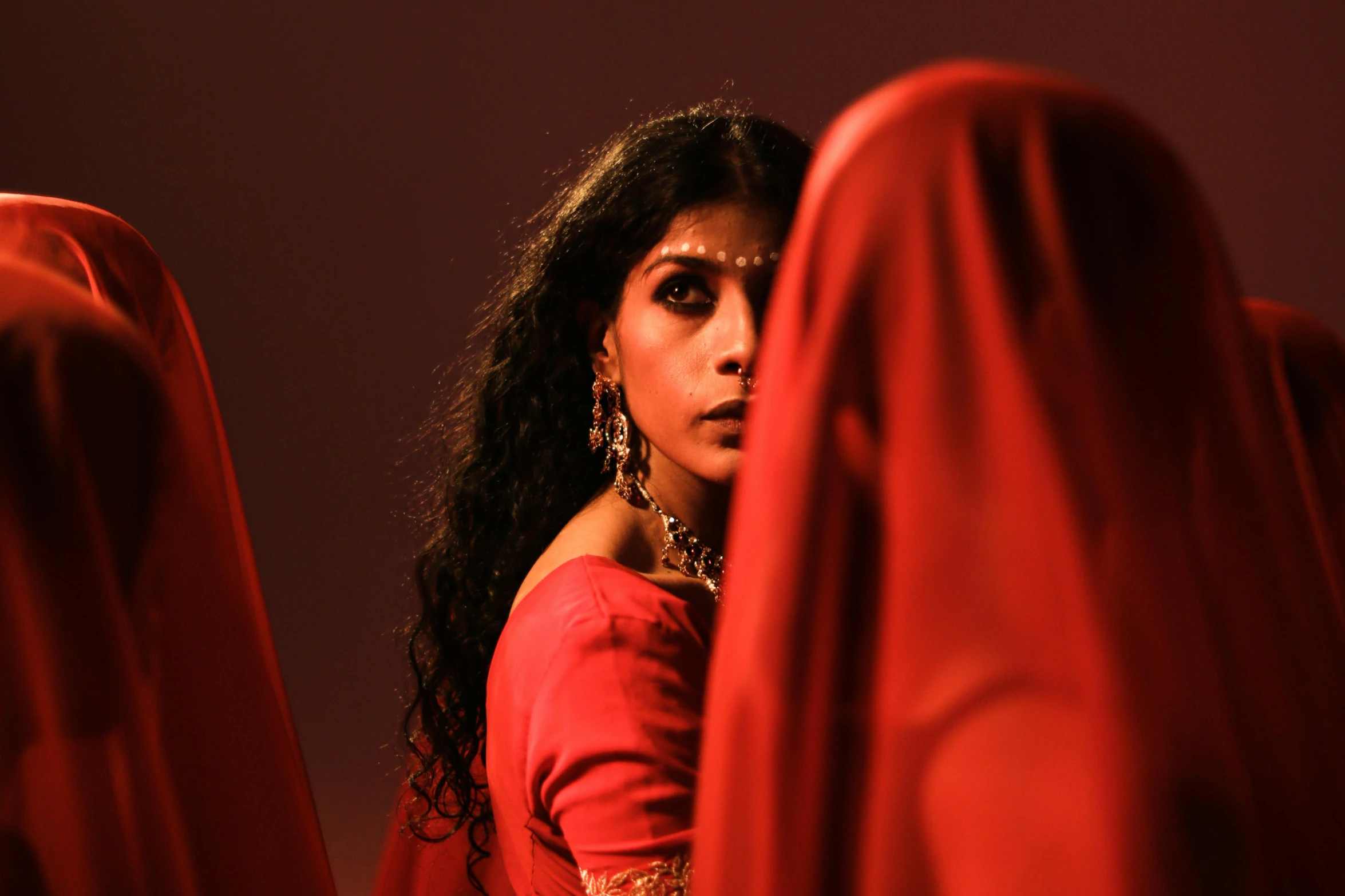 a woman in a red dress sitting in a red chair, an album cover, inspired by Edwin Austin Abbey, pexels contest winner, renaissance, the eyes of sharbat gula, 3 actors on stage, ( ( theatrical ) ), provocative indian