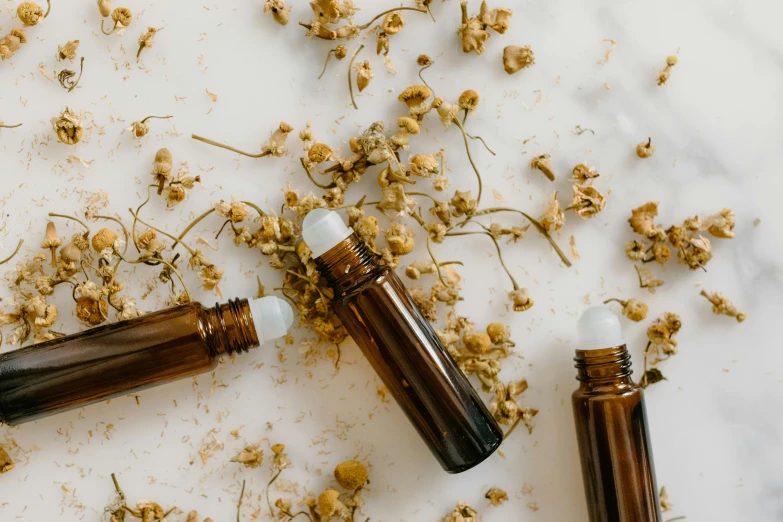 a couple of bottles sitting on top of a table, trending on pexels, brown flowers, healing tubes, chamomile, profile image