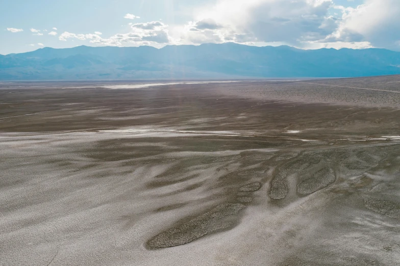 a view of a desert with mountains in the distance, inspired by Andreas Gursky, unsplash contest winner, land art, death valley, river delta, background image, view from helicopter