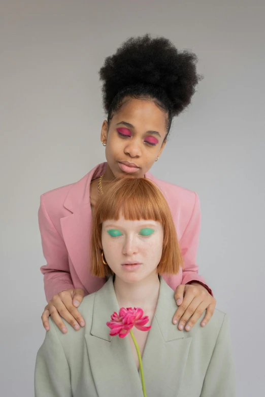 a couple of women standing next to each other, an album cover, by Cosmo Alexander, trending on pexels, with red hair and green eyes, wearing a light - pink suit, mix of ethnicities and genders, lily frank