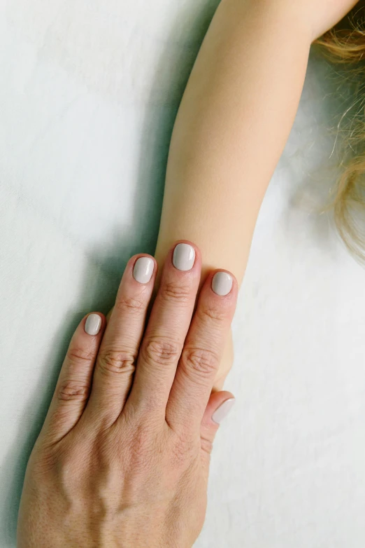 a close up of a person with a hand on a table, pale gray skin, painted nails, muted arm colors, kid named finger