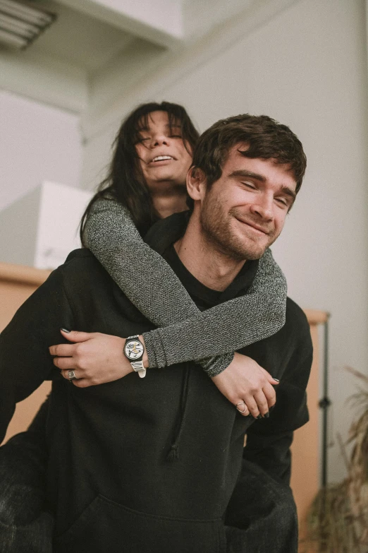 a man carrying a woman on his back, pexels contest winner, bo burnham, arm around her neck, indoor, happy friend