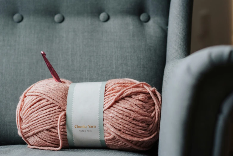 a ball of yarn sitting on top of a chair, inspired by Charles Roka, trending on pexels, light pink, material pack, label, cinnabar