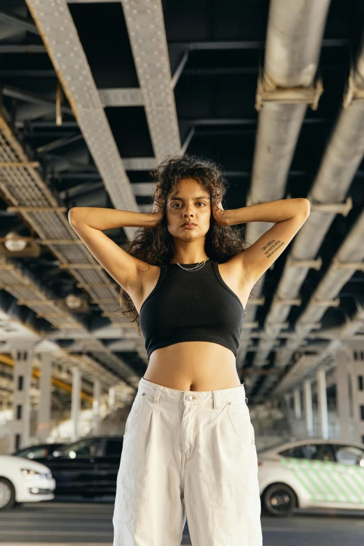 a woman in a black top and white pants, pexels contest winner, industrial aesthetic, wearing : tanktop, mixed-race woman, cynthwave